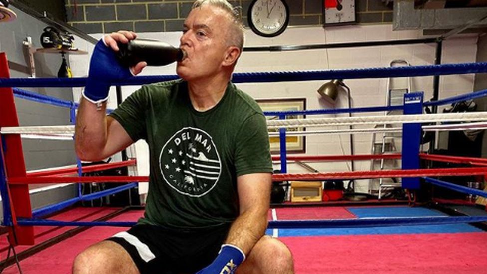 Huw Edwards drinking water outside a boxing ring