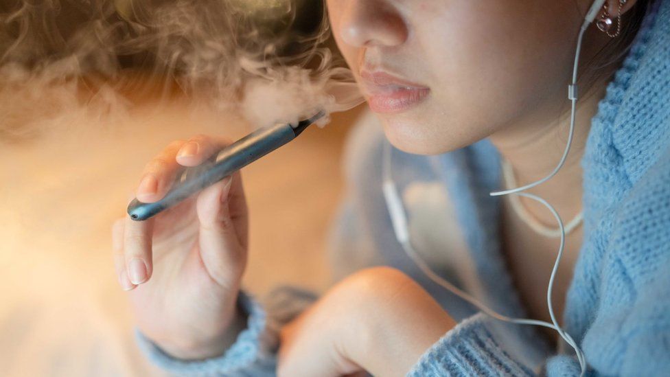 Stock image of a young woman vaping