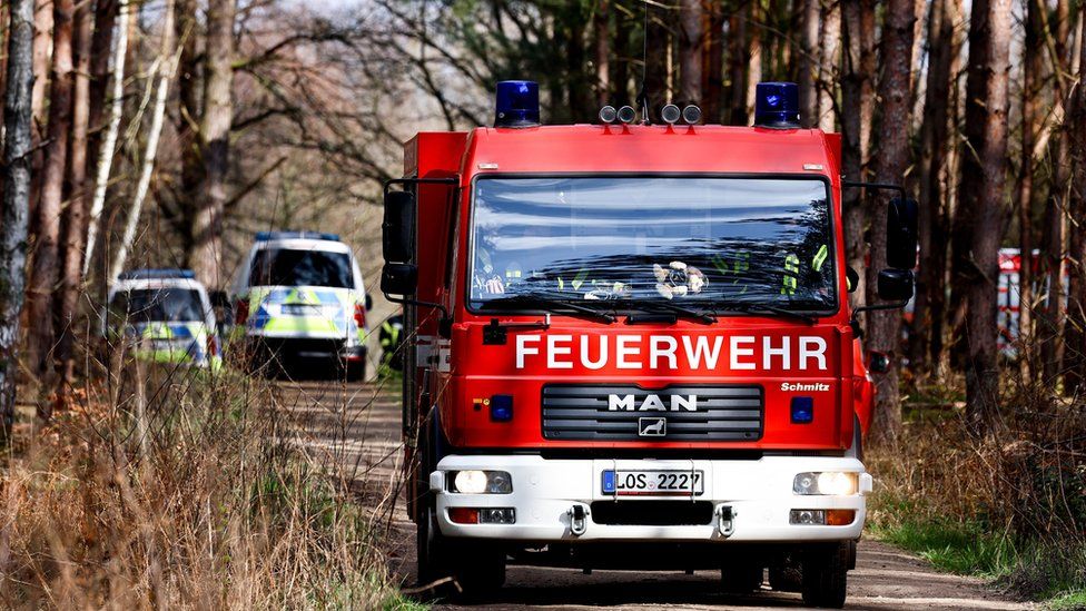 A red fire engine drives through the forest