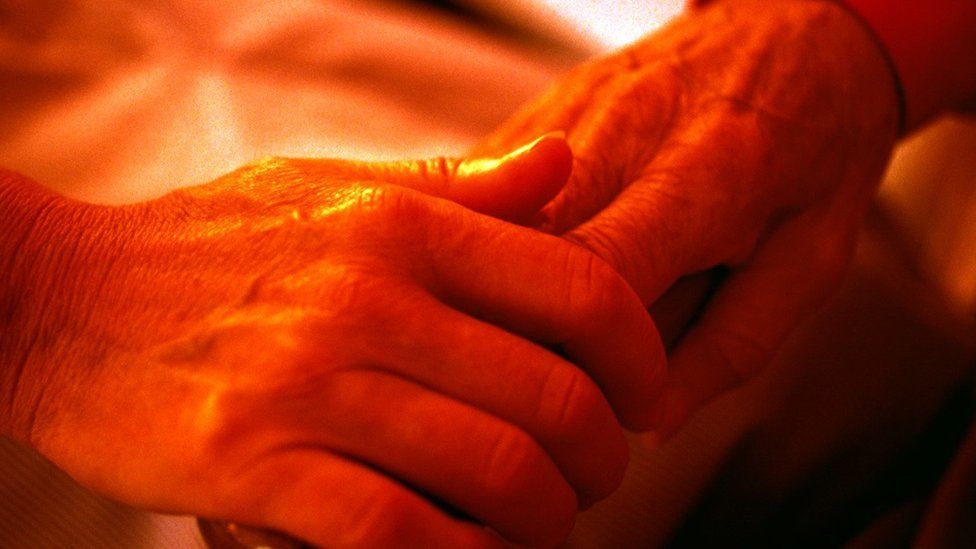 Nurse holding the hand of an elderly patient