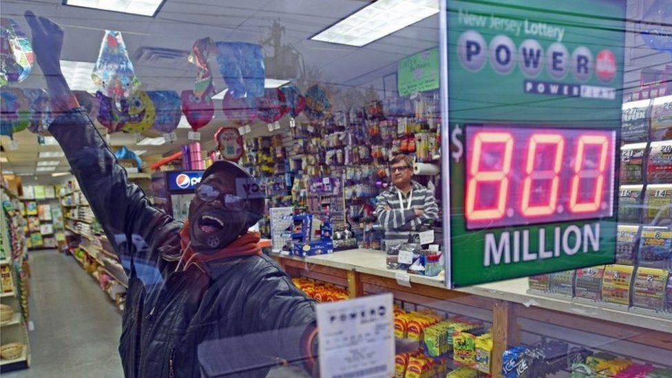 An optimistic lottery ticket buyer in New Jersey shows off his Power Ball ticket through a shop window (09 January 2016)