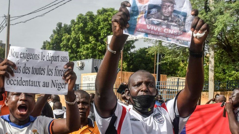 A supporter holds a picture of Niger General Abdourahamane Tiani, the chief of the powerful presidential guard, as with others rally in support of Niger's junta in Niamey on July 30, 2023
