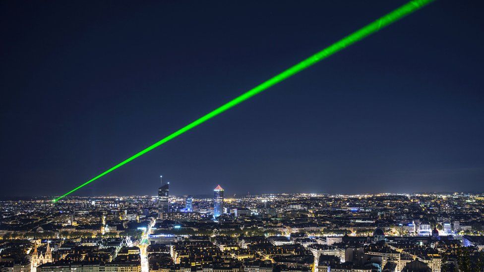 A bright green laser beam shining in the night sky above Lyon, France