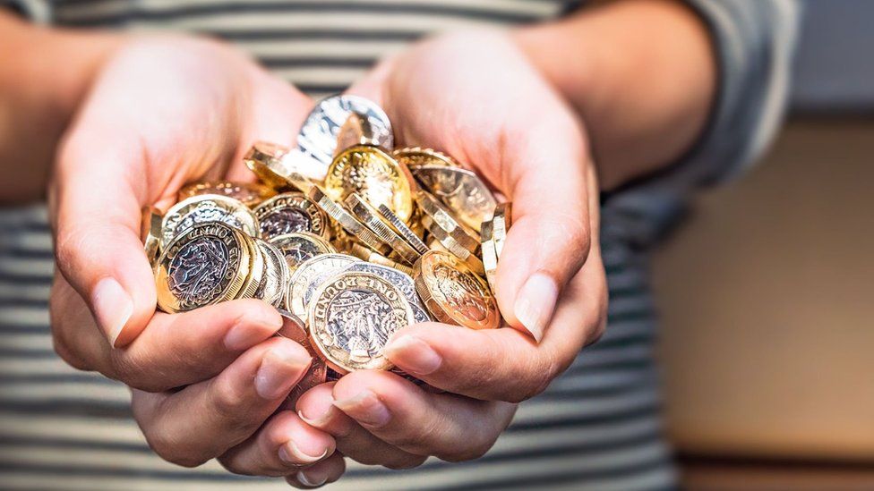 Hands holding pound coins