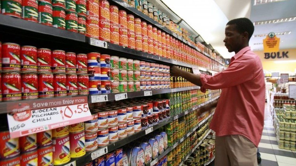A Zimbabwean shop worker displays food cans in a supermarket in Harare (13 October 2010)