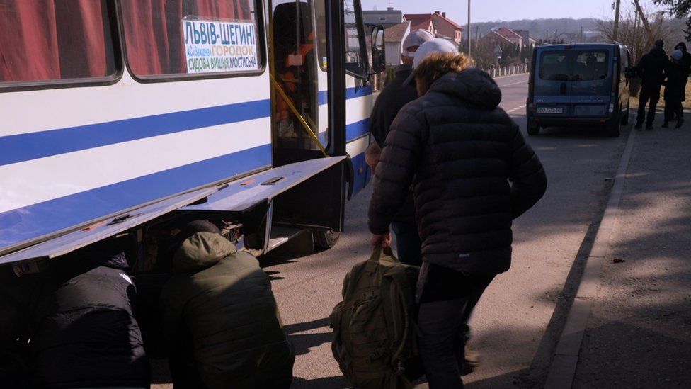 British ex-soldiers load luggage into a bus