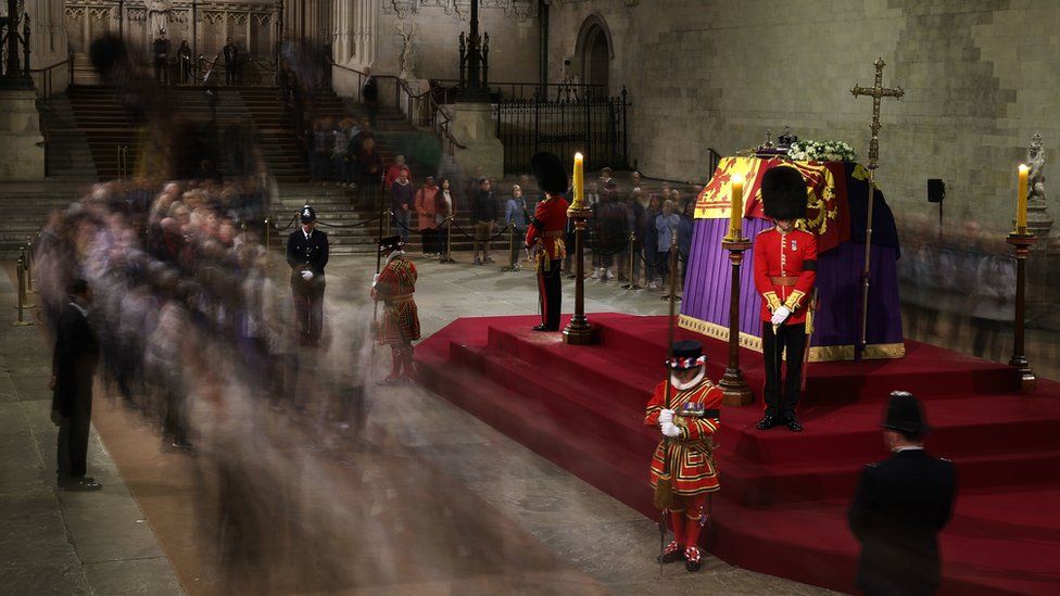 Представители общественности рассматривают гроб королевы Елизаветы II, лежащий на катафалке в Вестминстер-холле, в Вестминстерском дворце, Лондон, перед ее похоронами в понедельник