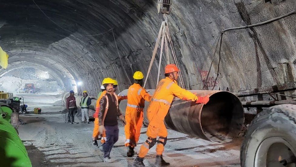 Rescuers work with equipment to reach the workers inside the tunnel