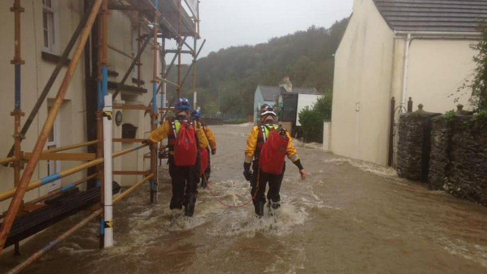 Coastguards walking through flooded street