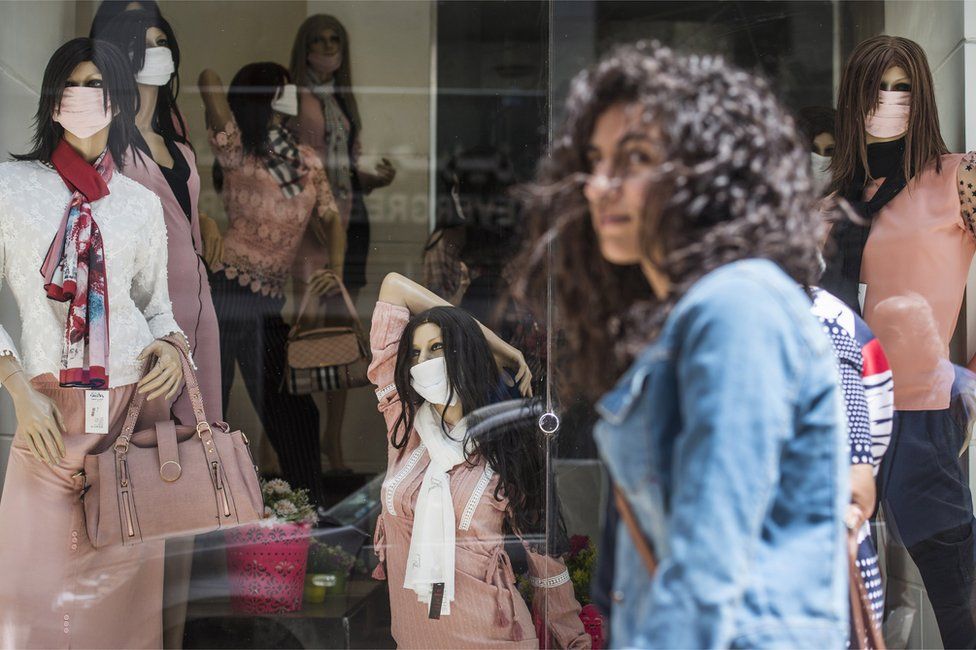 A woman passes in front of mannequins in a shop wearing face masks in street in Cairo, Egypt, on 25 April.