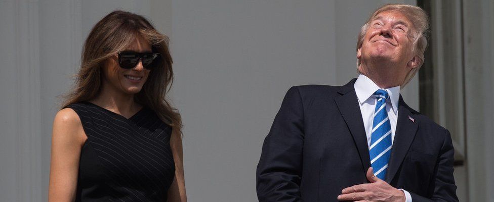US President Donald Trump, with First Lady Melania Trump at his side, looks up at the partial solar eclipse from the balcony of the White House in Washington, DC, on August 21, 2017