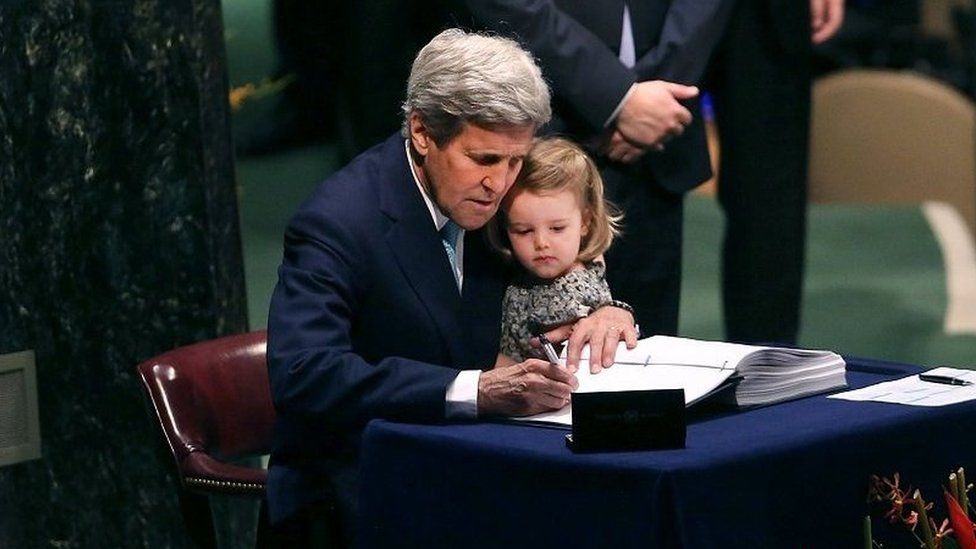 John Kerry is joined by his granddaughter as he signs the Paris climate agreement in 2016