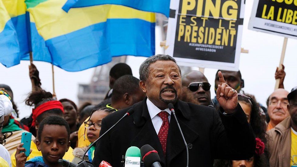 Jean Ping (C), surrounded by supporters waving Gabonese flags, gestures as he speaks on October 29, 2016 on the Human Rights Esplanade, at the Place du Trocadero in Paris, one month after incumbent president's victory in Gabonese presidential election was controversially validated by the constitutional court