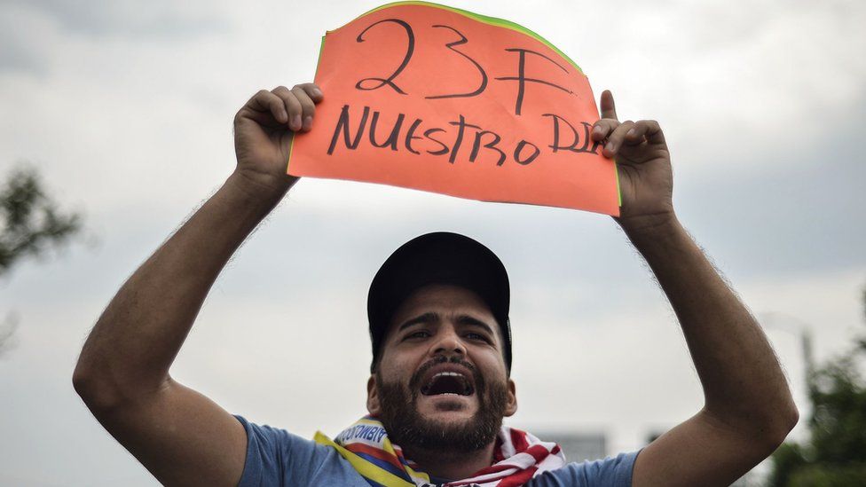 A man holds a placard reading "23F Our Day"