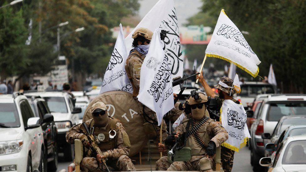 Taliban fighters holding Islamic Emirate of Afghanistan flags