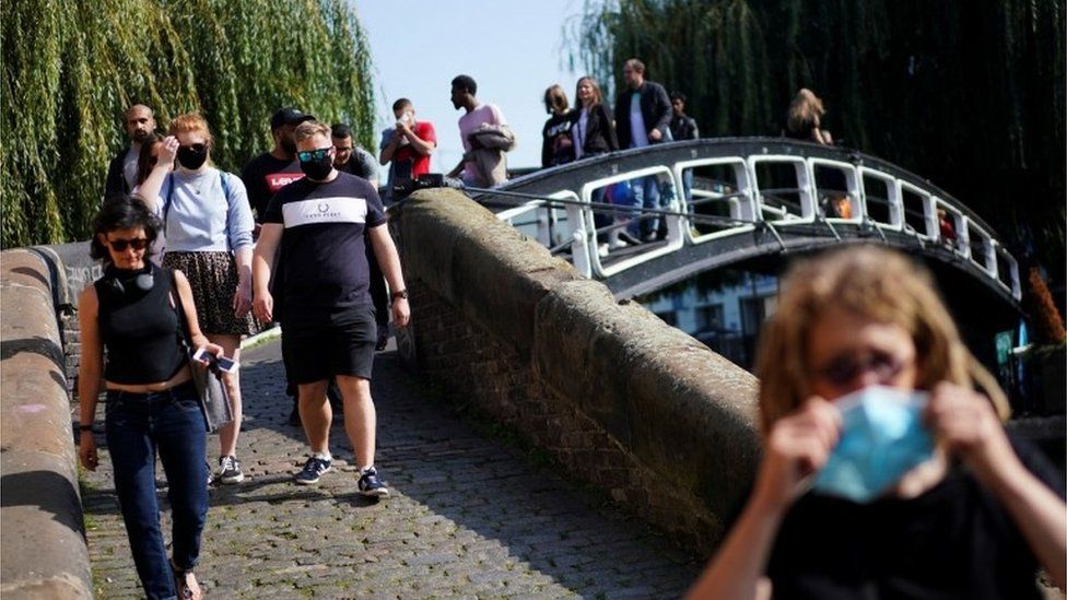 People walk along the bank of Regents Canal, London