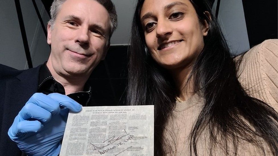 Spencer and Dhara pose with a copy of the Outer Space Treaty