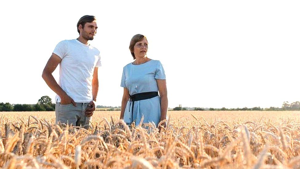 Nadiya and her son Dmytro standing in one of their wheat fields.