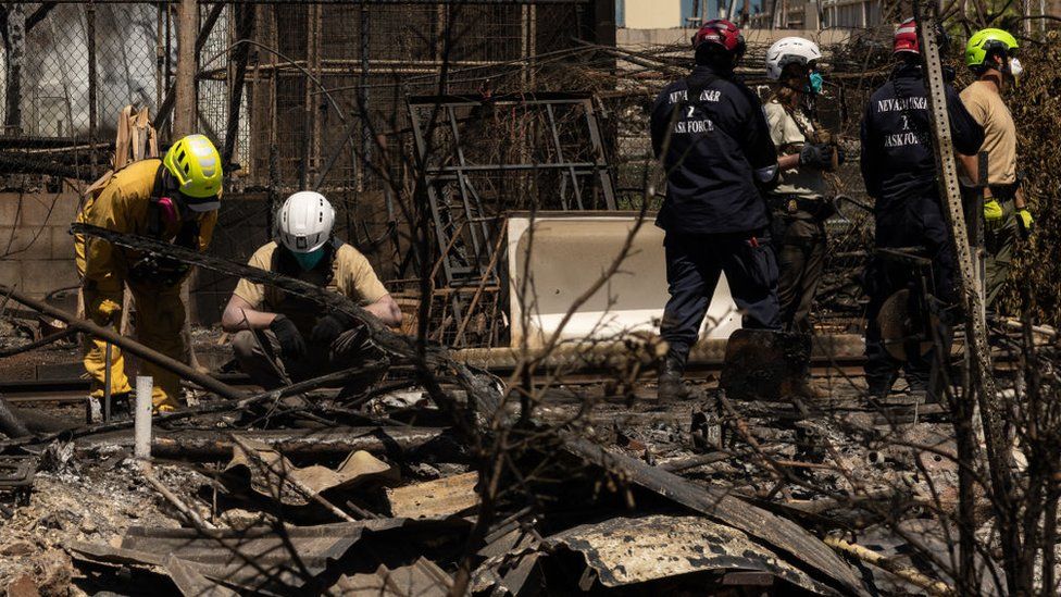 Search and recovery team members check charred buildings and cars in the aftermath of the Maui wildfires in Lahaina