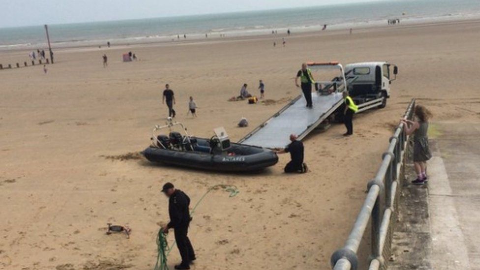 Border Control officials packing up a boat on a beach in Dymchurch, Kent
