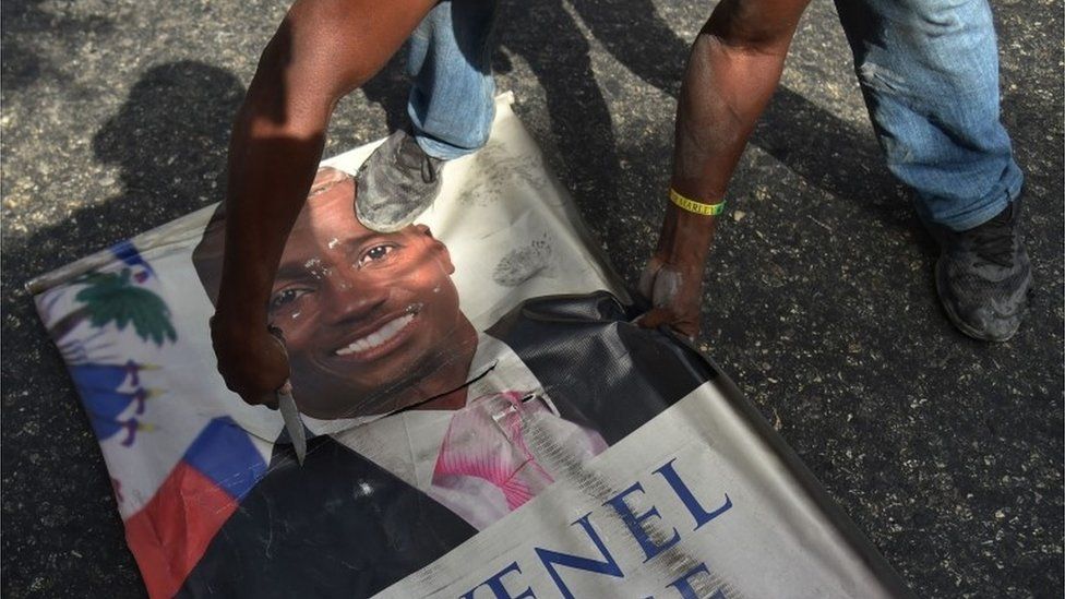 Protesters destroy a poster of Haitian President Jovenel Moise as they demonstrate in the Port-au-Prince suburb of Petion-Ville on July 7, 2018, against a hike in fuel prices.