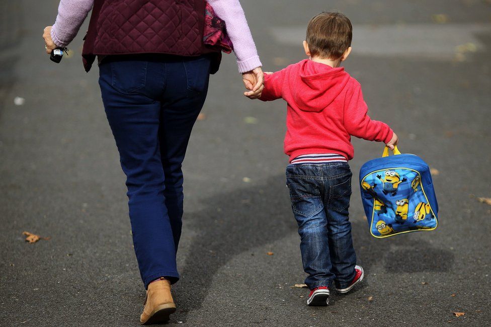 Woman holds child's hand