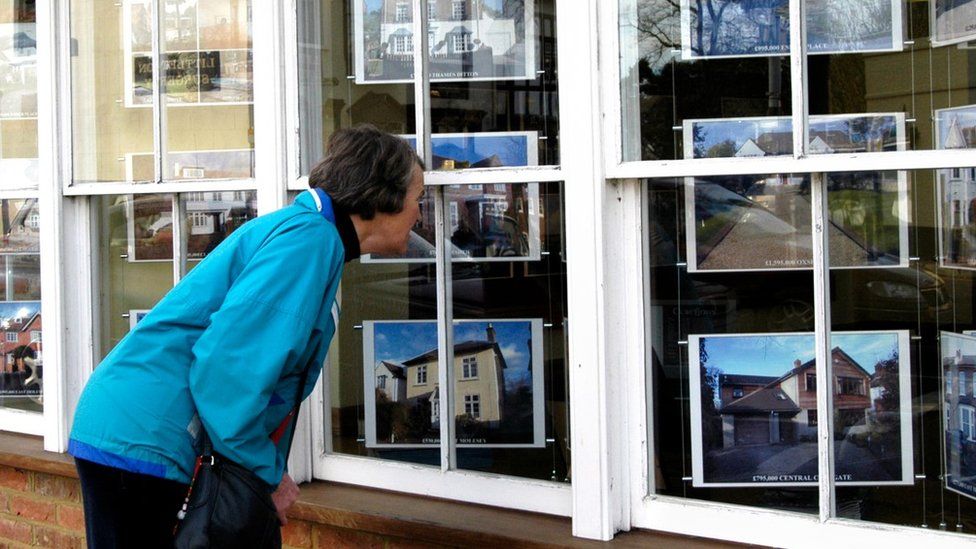 Woman peering into estate agents window