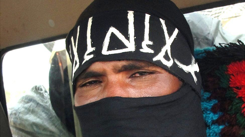 A close-up shot of an Islamist militant wearing a black fabric on his face showing only his eye.