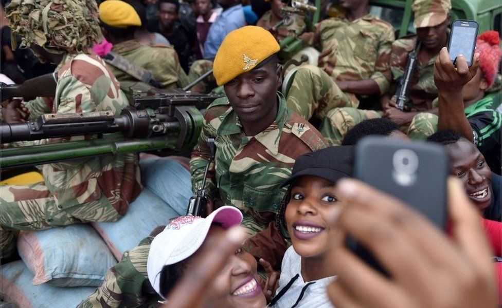 A Zimbabwean Defence Force soldier poses for selfie-pictures with two women as they take part in a march in the streets of Harare, on November 18, 2017 to demand to the 93 year-old Zimbabwe"s president to step down. Zimbabwe"s president clings to office, the military is in power and the much-feared ZANU-PF party still rules - but Zimbabweans put such issues aside on November 18, 2017 to happily embrace what they hope is a new era for the country.