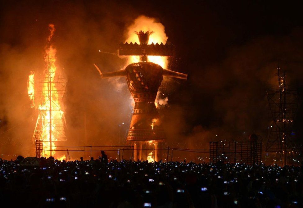 Индуистские преданные наблюдают за горящим изображением короля демонов Раваны, начиненного петардами, в Амритсаре 19 октября 2018 года по случаю индуистского фестиваля Душера.