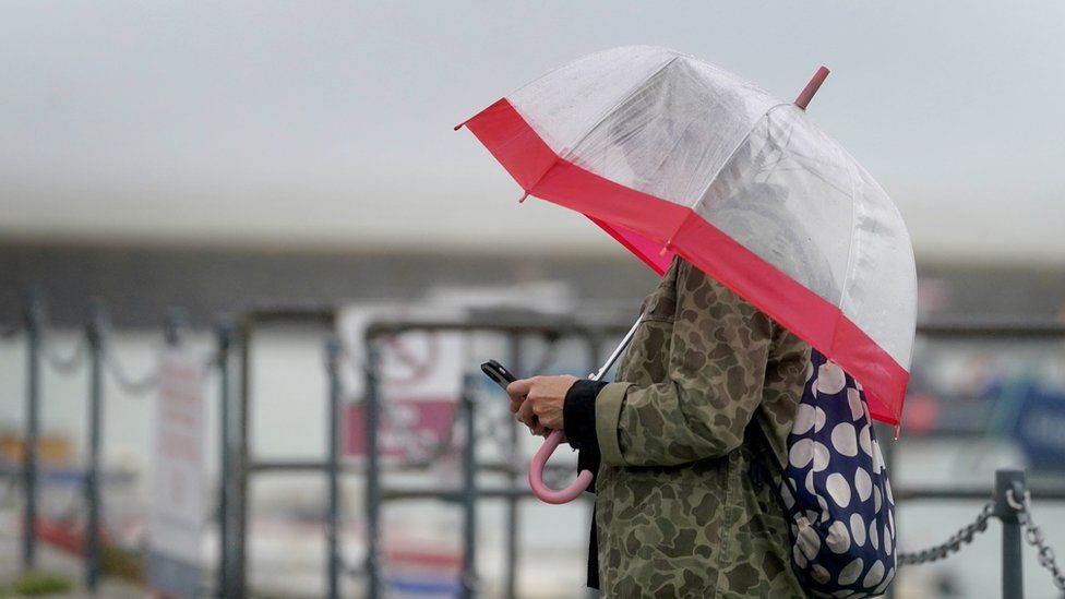 A shelters under an umbrella during bad weather in Folkestone, Kent. Picture date: Monday July 31, 2023.