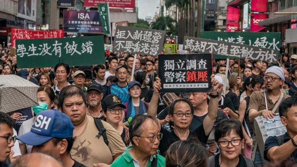 Protesters hold placards and shout slogans as they take part in a rally on a street on July 7, 2019 in Hong Kong