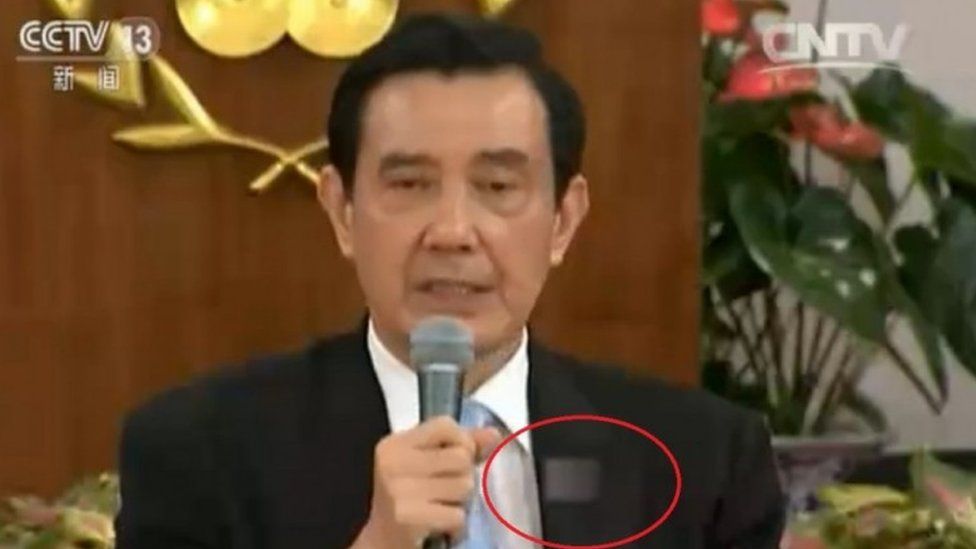 TV screengrab showing a man with a blurred Taiwanese emblem on his jacket