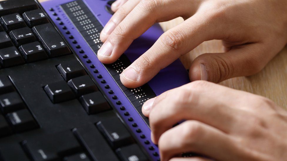 Hands on a keyboard with a braille computer display