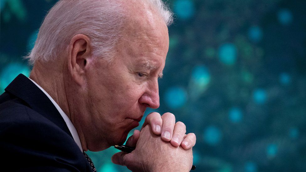 President Biden looking thoughtful with hands clasped