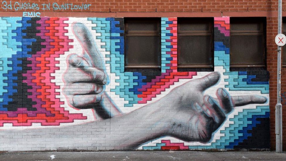 A mural of two hands on a coloured background