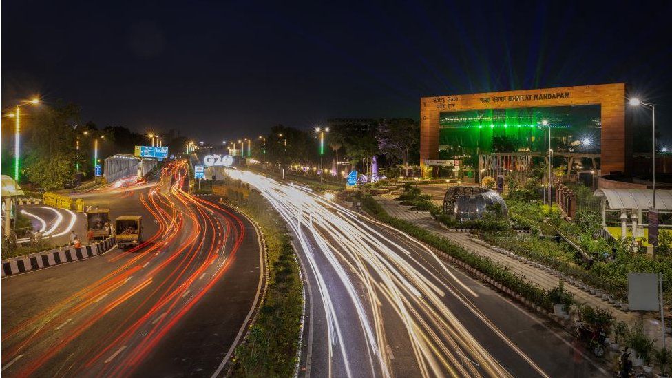 Traffic moves past a G20 logo installed in front of the main venue of the summit in New Delhi, India, August 25, 2023.