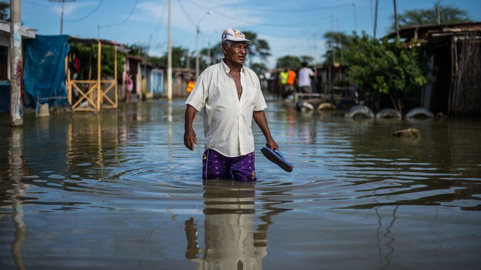 Persona caminando en una calle inundada en una población rural de América Latina