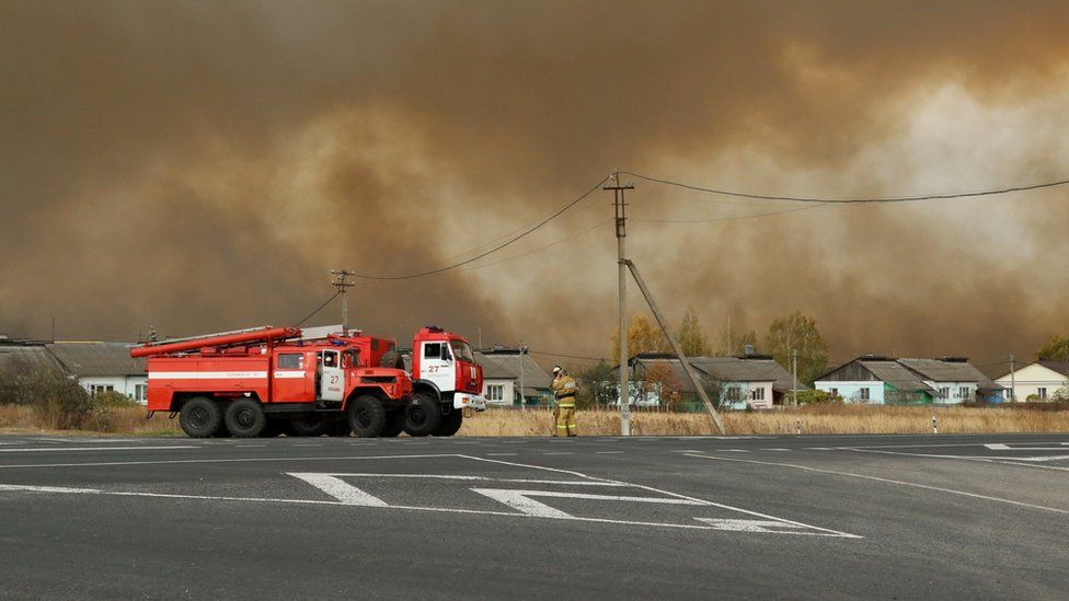 Fire trucks on the road as smoke rises from the site of a fire at an ammunition depot in Ryazan region, Russia, 7 October 2020