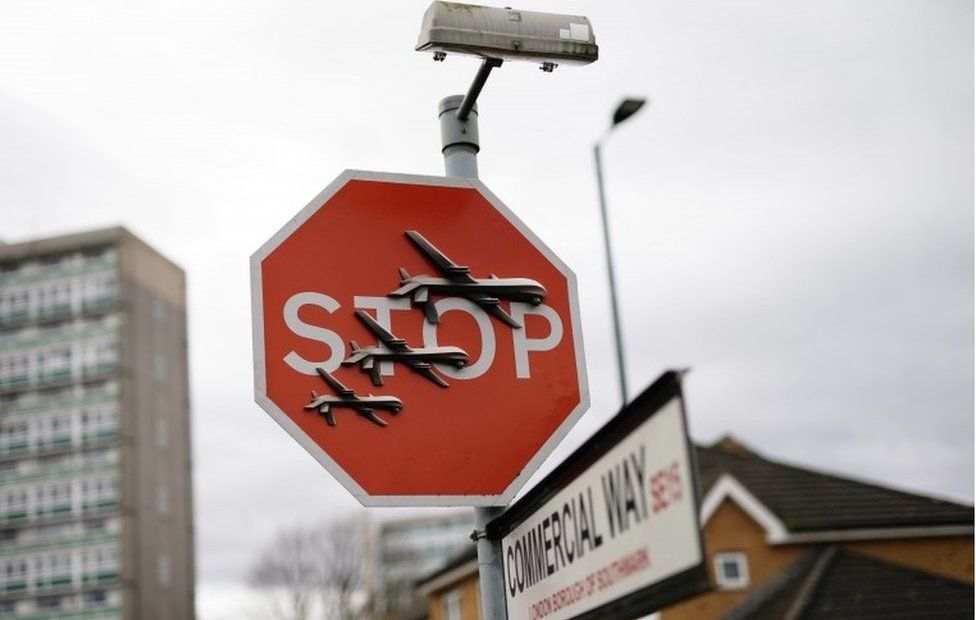 Banksy artwork in Peckham. Three models of reaper drones have been attached to a red stop traffic sign.