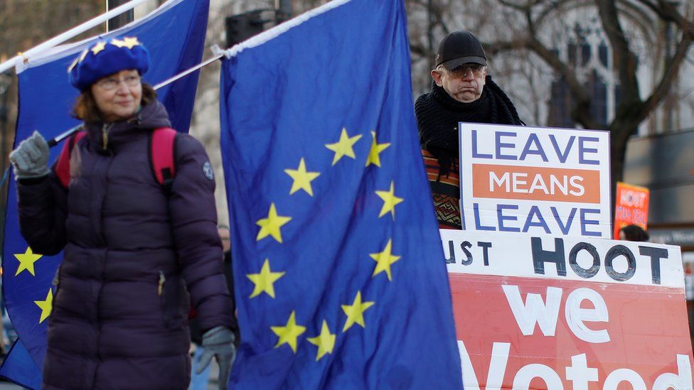 Anti-Brexit activists (L) and a pro-Brexit activist (R), hold placards and flags as they demonstrate near the Houses of Parliament