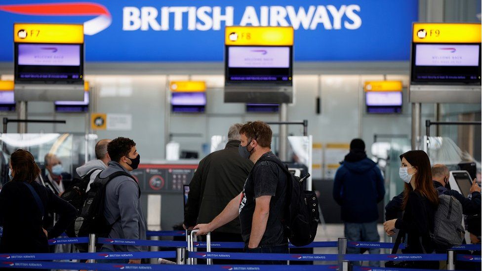 Passengers stand in a queue to the British Airways check-in desks at Heathrow Airport