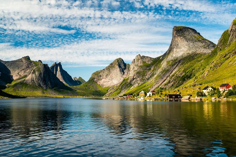 A landscape view over a lake with some buildings and mountains in the background