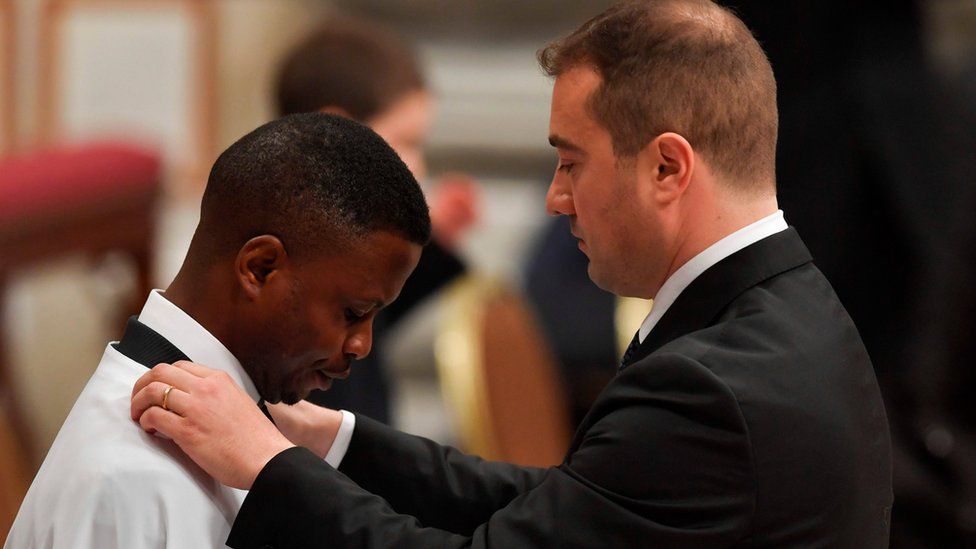 Nigerian John Ogah (L), 31, stands in front of his godfather Italian carabinieri Nunzio Carbone (R), after being baptised by Pope Francis in the Vatican.