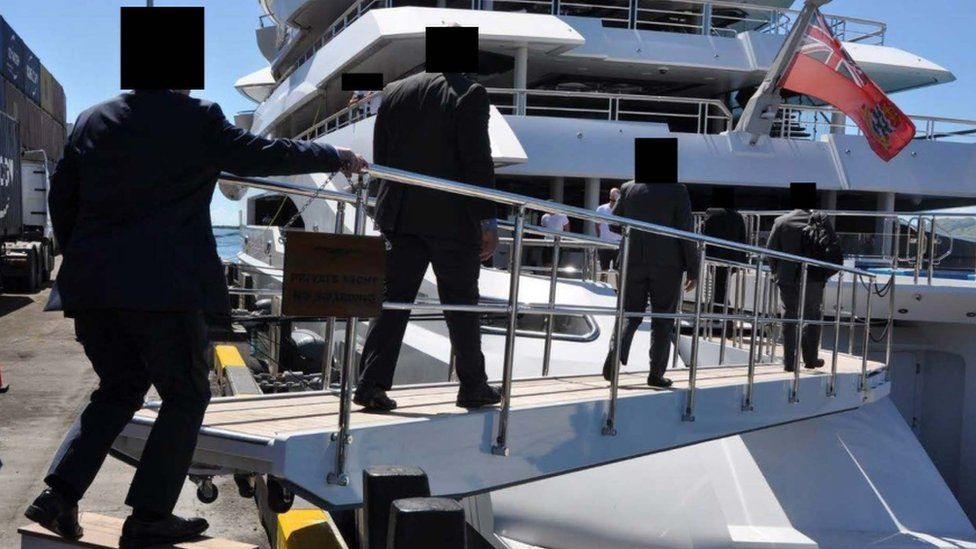 Law enforcement officers walk on to the Amadea superyacht