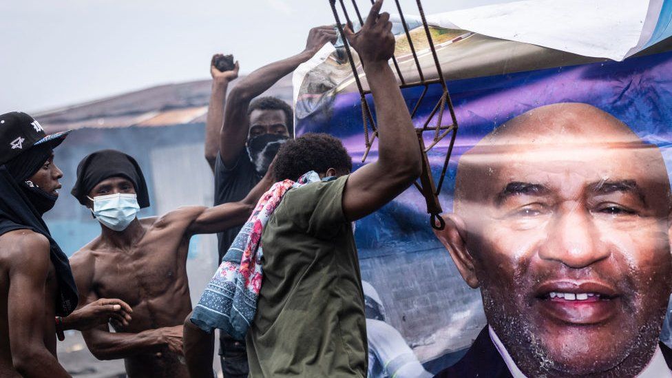 Opposition supporters destroy a billboard image of incumbent Comoros President and president of Convention for the Renewal of Comoros (CRC), Azali Assoumani, during a demonstration in Moroni on January 17, 2024