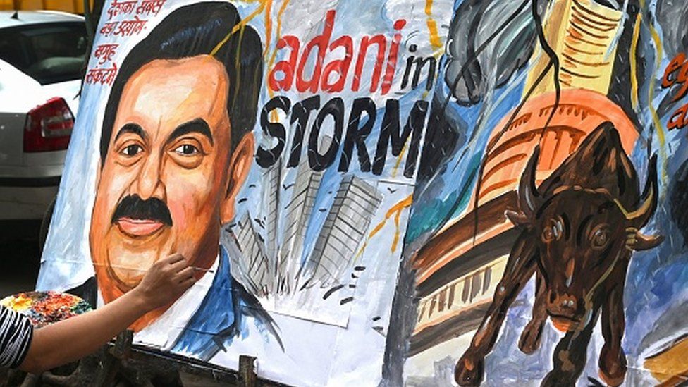 An art school teacher gives final touches to a painting of Gautam Adani, highlighting the ongoing crisis of the Adani group in Mumbai