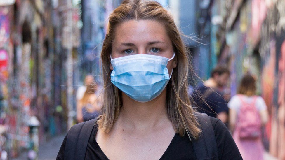 A woman with mask in one of Melbourne's iconic graffiti-filled laneways