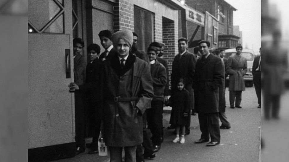 Indian men queuing outside a building