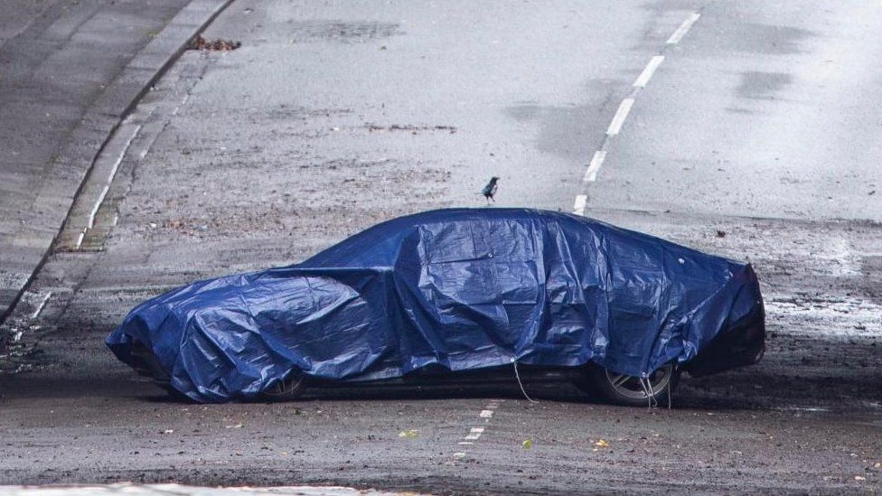 Image shows covered car under a bridge